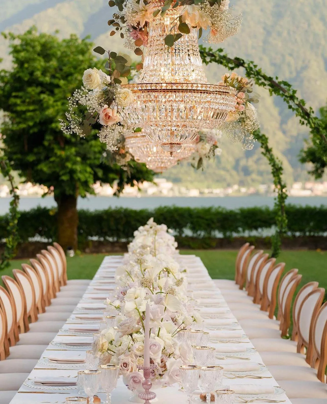 Outdoor wedding dinner set beneath crystal chandeliers